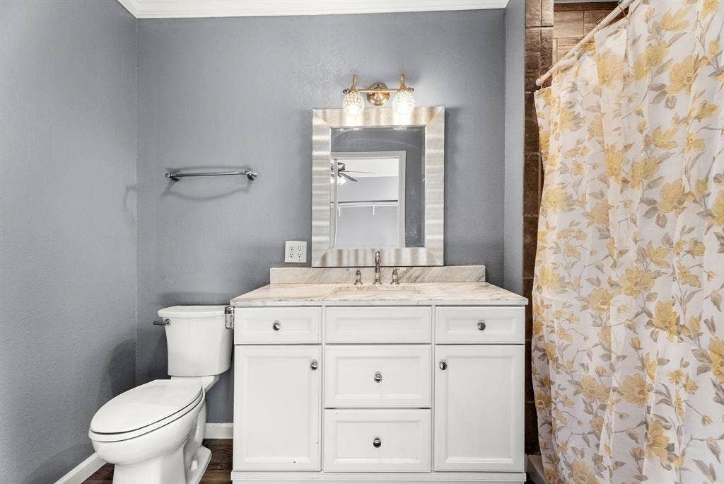 605 Dallas Street, Winona, TX 75792 White vanity with stone countertop and integrated sink, chrome faucet, and rectangular mirror