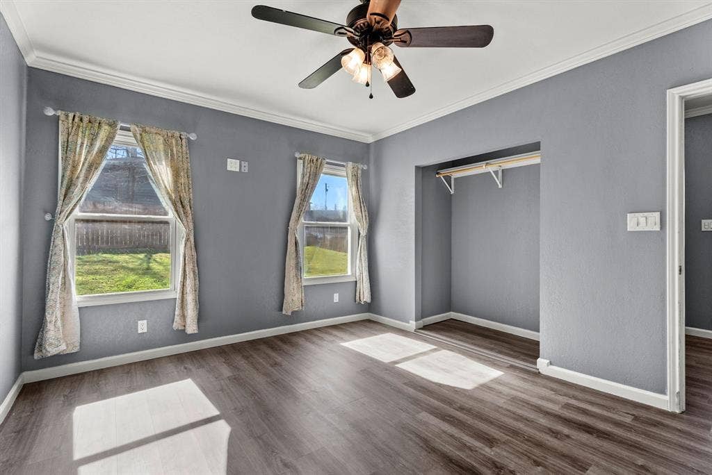 605 Dallas Street, Winona, TX 75792 Wood-finish flooring throughout, crown molding, two windows with exterior views, and a ceiling fan with integrated lighting