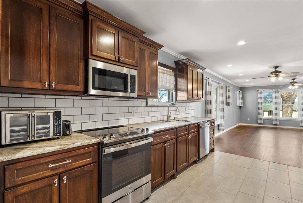 605 Dallas Street, Winona, TX 75792 Dark wood-finish cabinetry, stainless steel appliances, subway tile backsplash, and light-colored countertops