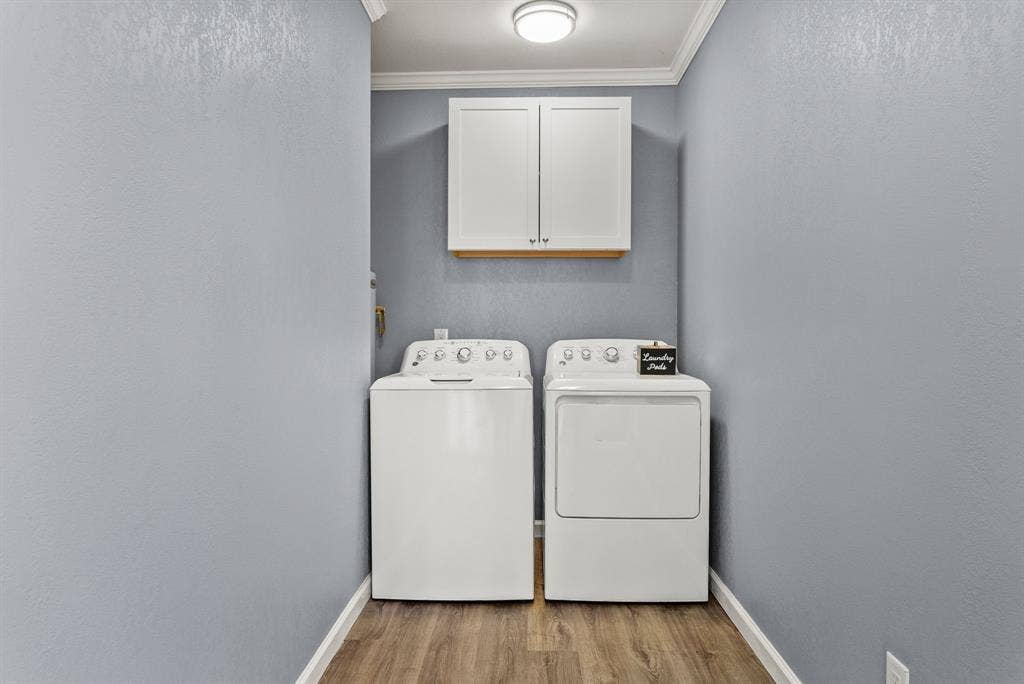 605 Dallas Street, Winona, TX 75792 Laundry area featuring wood-finish flooring, overhead cabinetry, and crown molding