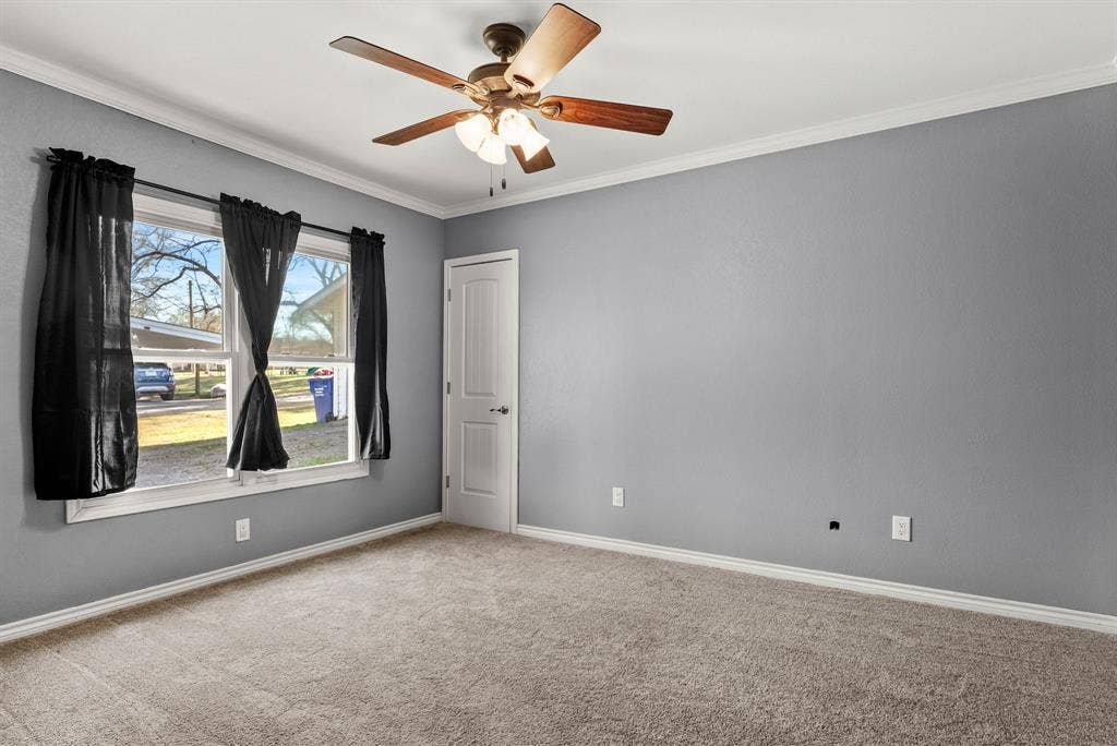 605 Dallas Street, Winona, TX 75792 Expansive room featuring neutral-toned carpeting, a ceiling fan with integrated lighting, and a white paneled door