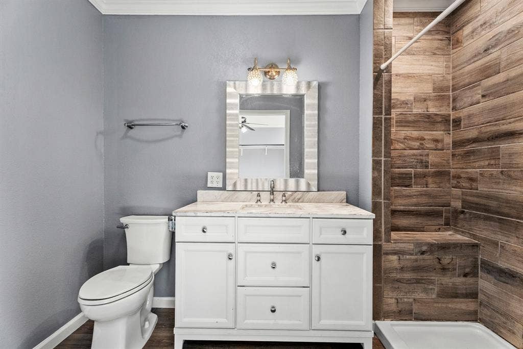 605 Dallas Street, Winona, TX 75792 White vanity with a light-toned countertop, a decorative mirror, and a wall-mounted light fixture