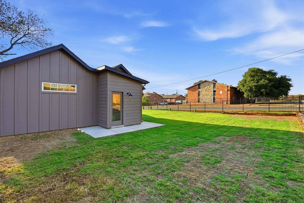 1601 Birdell Street, Fort Worth, TX 76105 Manicured lawn with a concrete patio and direct access door, featuring board and batten siding and a horizontal window