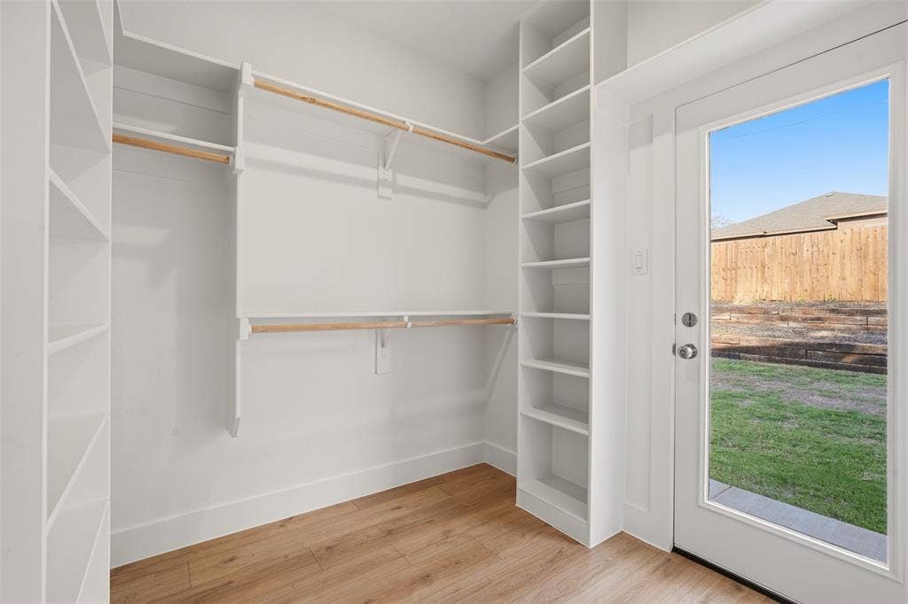 1601 Birdell Street, Fort Worth, TX 76105 White built-in shelving, natural wood finish hanging rods, wood-finish flooring, and a glass-paneled door