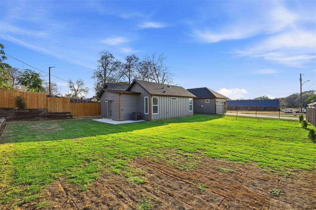 1601 Birdell Street, Fort Worth, TX 76105 Expansive rear yard featuring green lawn, privacy fencing, a concrete patio, and a detached structure