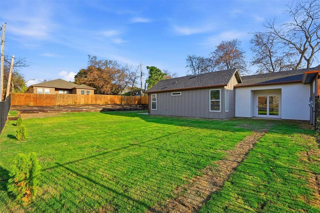 1601 Birdell Street, Fort Worth, TX 76105 Expansive backyard featuring a manicured lawn, wood fencing, and a contemporary exterior with sliding glass doors