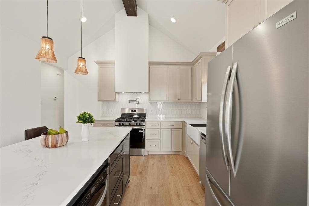 1601 Birdell Street, Fort Worth, TX 76105 Vaulted ceiling with exposed beam, stainless steel appliances, white subway tile backsplash, farmhouse-style sink, and light wood-finish flooring