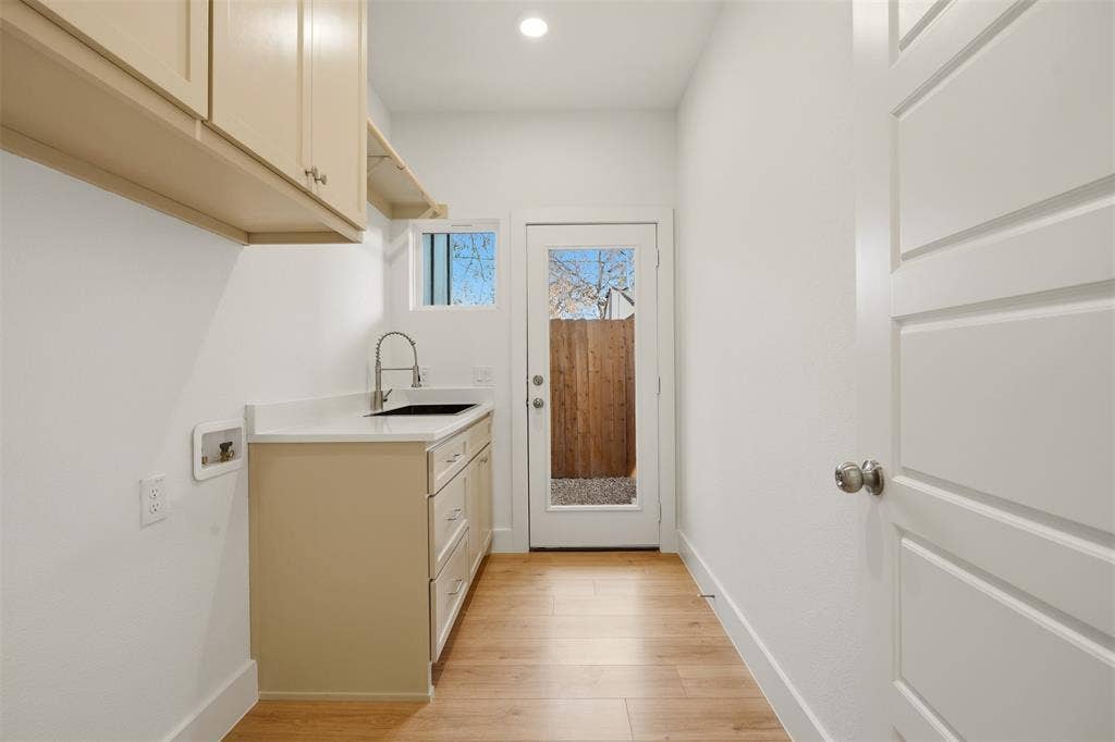 1601 Birdell Street, Fort Worth, TX 76105 Laundry area featuring wood-finish flooring, light-toned cabinetry, a built-in sink with a gooseneck faucet, a light-toned countertop, and a glass-paneled exterior door