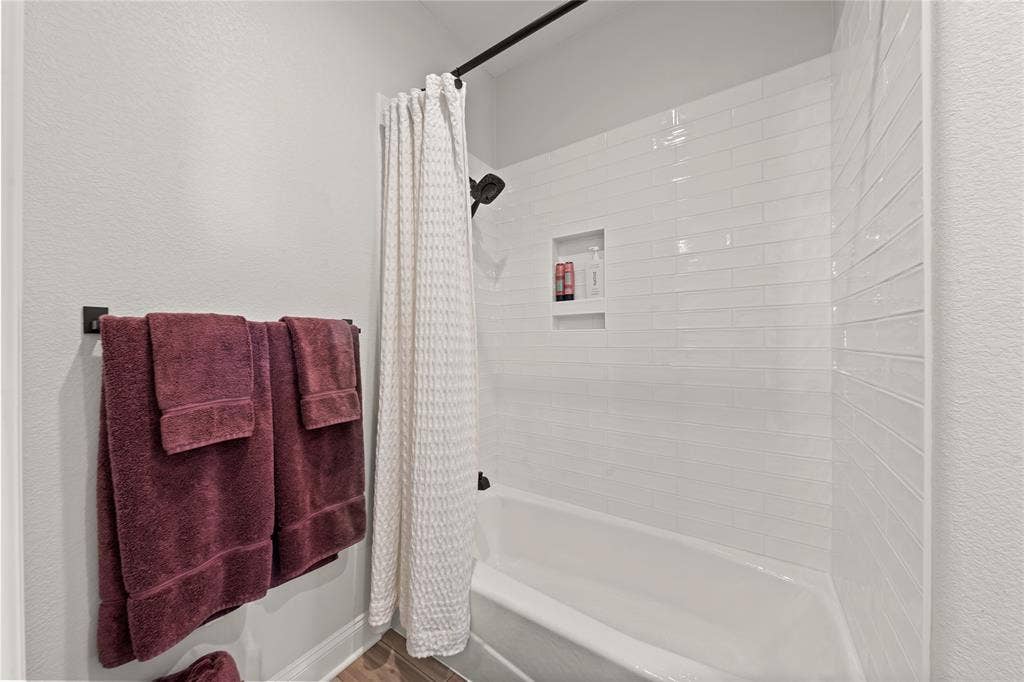 149 Water View Lane, Robinson, TX 76706 Bathtub with subway tile surround, integrated shower niche, and matte black shower fixtures