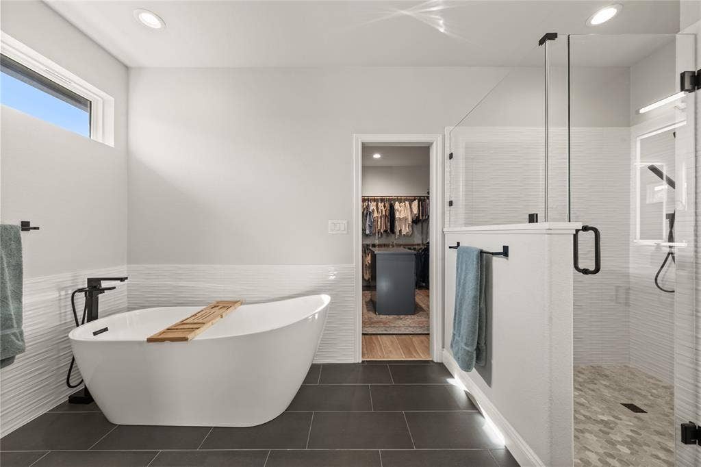 149 Water View Lane, Robinson, TX 76706 Freestanding soaking tub, walk-in shower with glass enclosure, dark tile flooring, textured wall tile, and recessed lighting
