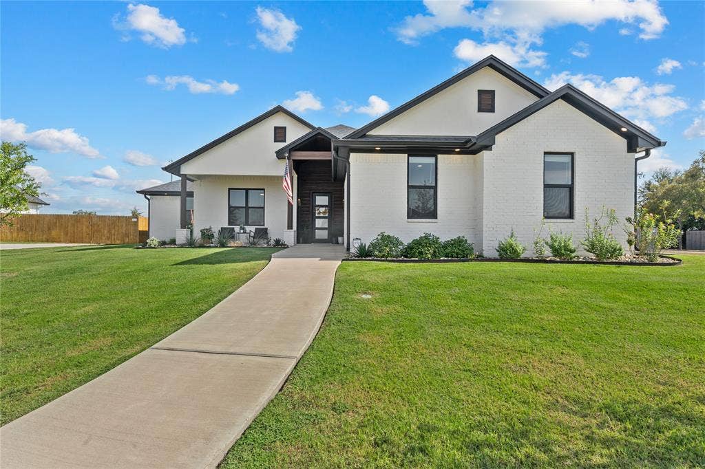 149 Water View Lane, Robinson, TX 76706 White brick exterior with black trim, dark-framed windows, a prominent entry porch, and a concrete pathway