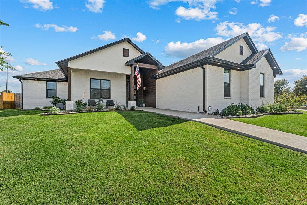 149 Water View Lane, Robinson, TX 76706 White brick exterior with dark trim, prominent gables, a covered entry, and a concrete walkway