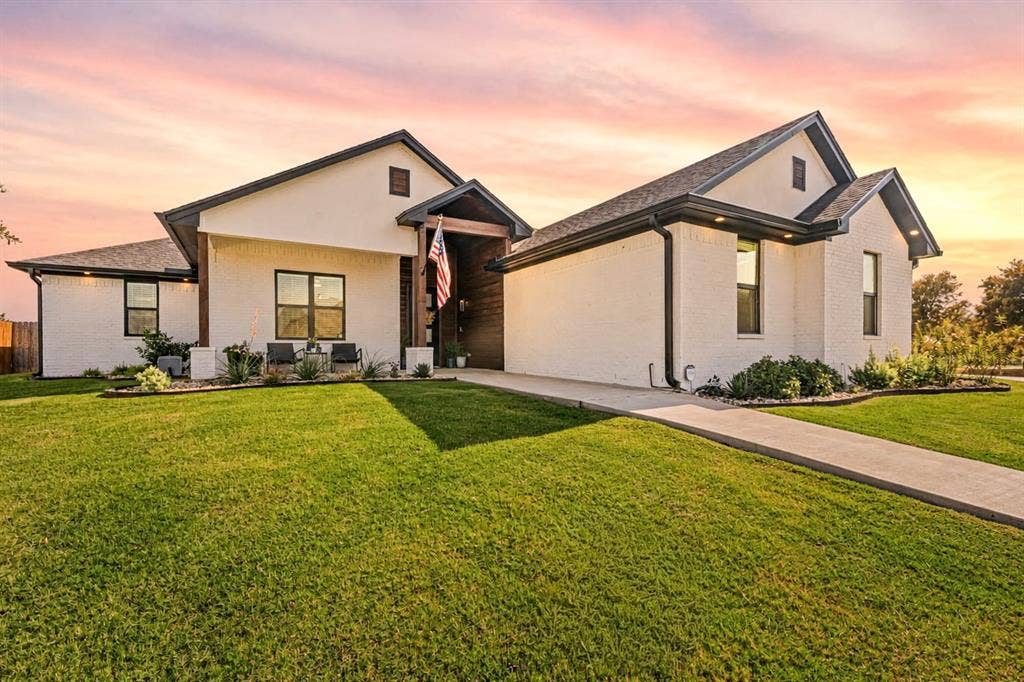 149 Water View Lane, Robinson, TX 76706 Contemporary exterior with white brick and dark trim accents, featuring a prominent front gable, a covered entry with wood-finish siding, and a concrete pathway