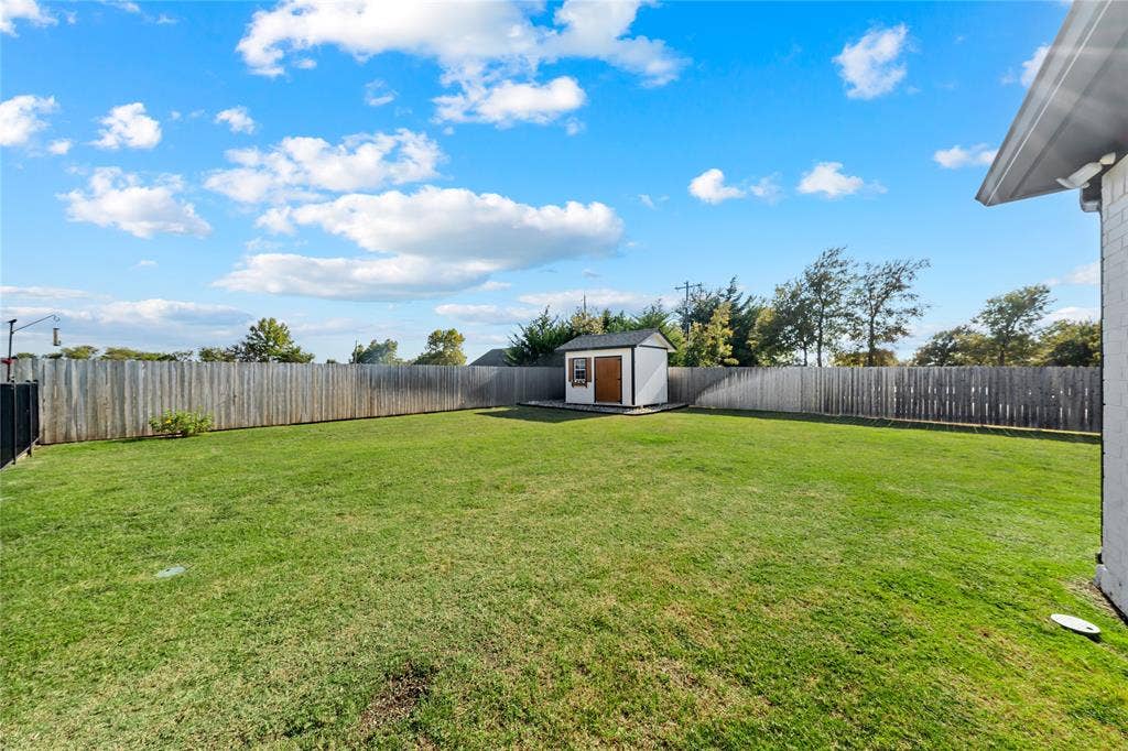149 Water View Lane, Robinson, TX 76706 Expansive fenced backyard featuring a manicured lawn and a utility shed with a gable roof