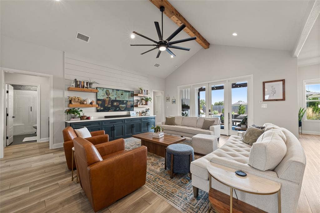 149 Water View Lane, Robinson, TX 76706 Vaulted ceiling with exposed wood beam, wood-finish flooring, built-in entertainment center with open shelving, large ceiling fan, and sliding glass doors