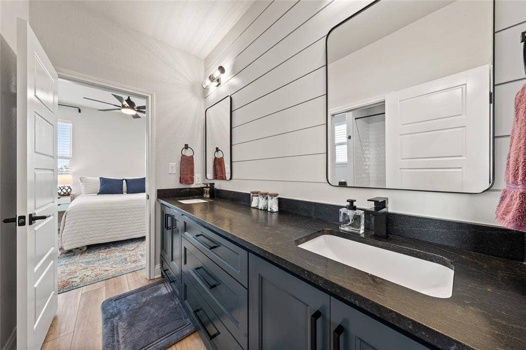 149 Water View Lane, Robinson, TX 76706 Dual vanity with an integrated sink, dark countertop, black fixtures, and shiplap accent wall