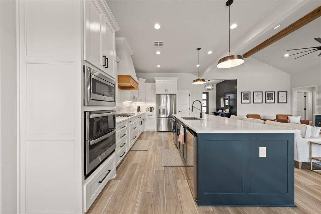 149 Water View Lane, Robinson, TX 76706 Kitchen featuring white shaker cabinetry, stainless steel appliances, a large center island with a dark base, light countertops, and wood-finish flooring