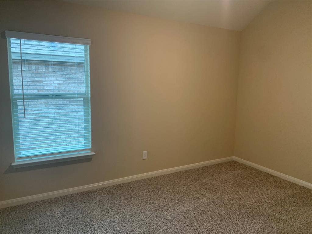 Carpeted flooring, neutral wall tones, window with horizontal blinds, and white trim