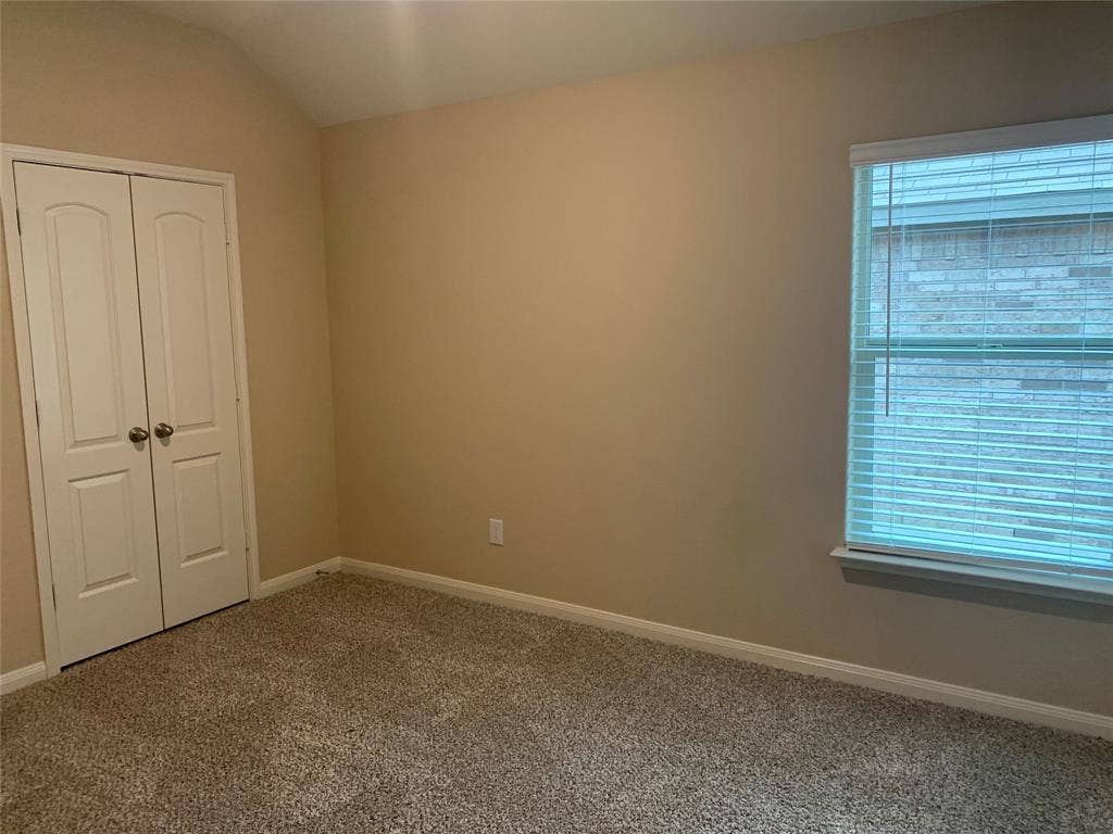 Carpeted room featuring a double-door closet, a window with horizontal blinds, and a neutral wall color