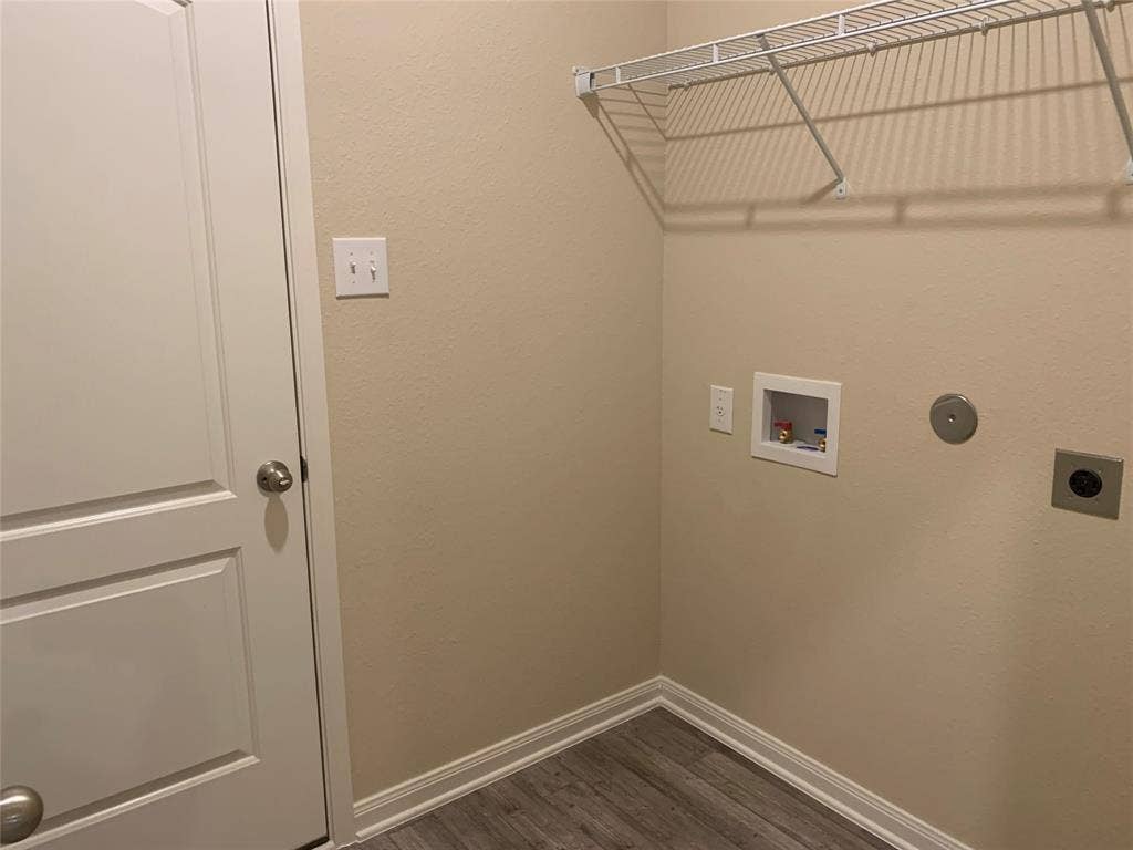Laundry area featuring wire shelving, utility hookups, and wood-finish flooring