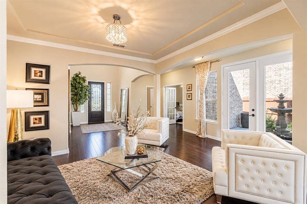 1704 Keswick Drive, McKinney, TX 75071 Tray ceiling with a decorative chandelier, wood-finish flooring, and French doors opening to an exterior fountain