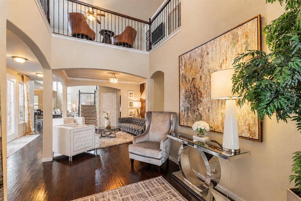 1704 Keswick Drive, McKinney, TX 75071 Double-height entry with dark wood-finish flooring, an open loft area with iron balusters, and arched doorways