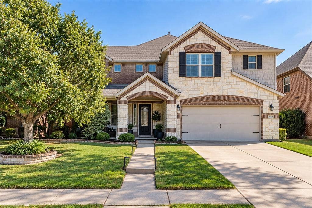 1704 Keswick Drive, McKinney, TX 75071 Two-story exterior with stone and brick facade accents, arched entry, attached garage, and landscaped front yard