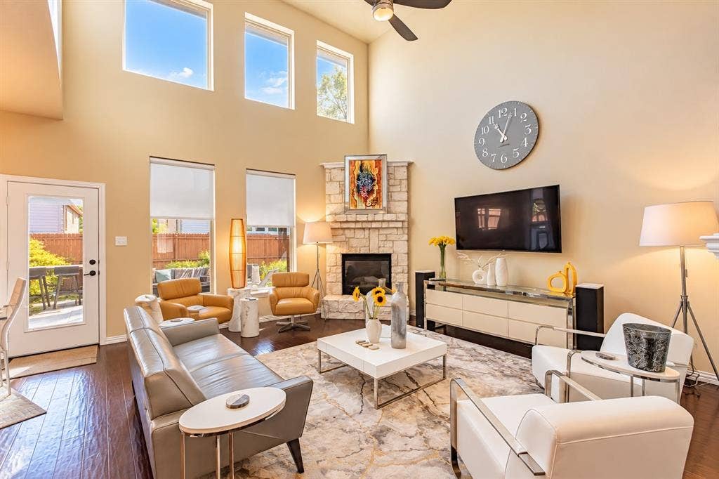 1704 Keswick Drive, McKinney, TX 75071 Two-story living area featuring a stone fireplace, wood-finish flooring, and a ceiling fan