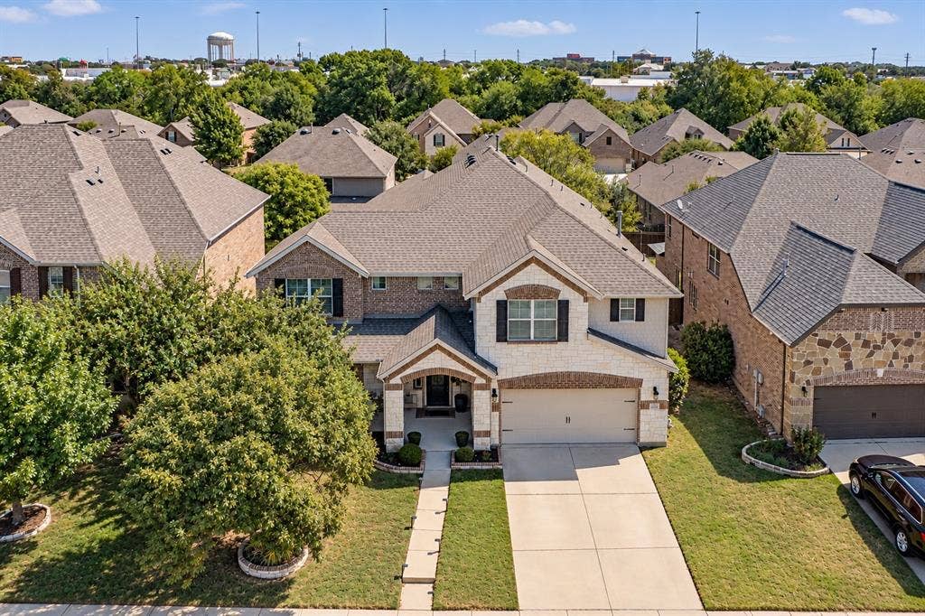 1704 Keswick Drive, McKinney, TX 75071 Stone and brick façade with a covered entry, attached garage, concrete driveway, and established landscaping