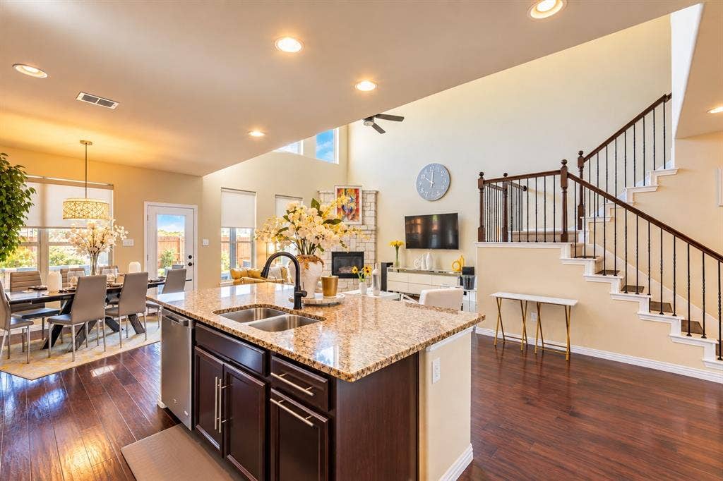 1704 Keswick Drive, McKinney, TX 75071 Kitchen island with granite countertop, integrated sink, and dark wood cabinetry