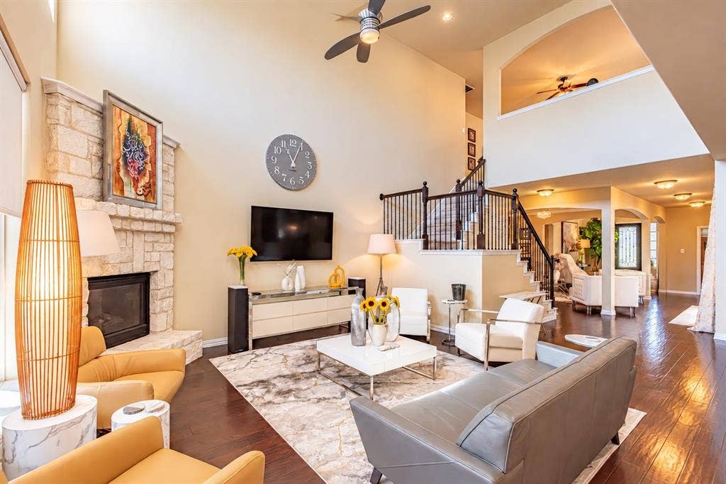 1704 Keswick Drive, McKinney, TX 75071 Soaring two-story living room featuring a fireplace with stone surround, recessed lighting, and hardwood flooring