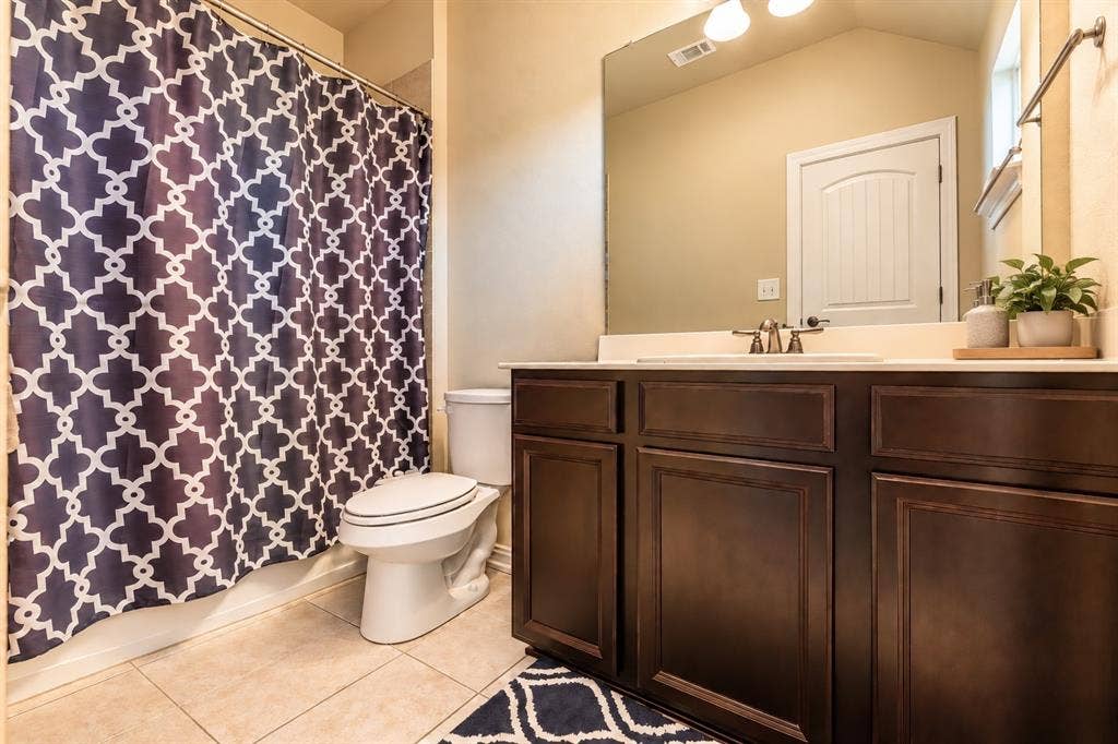 1704 Keswick Drive, McKinney, TX 75071 Full vanity with dark wood-finish cabinetry, integrated sink, and brushed nickel faucet
