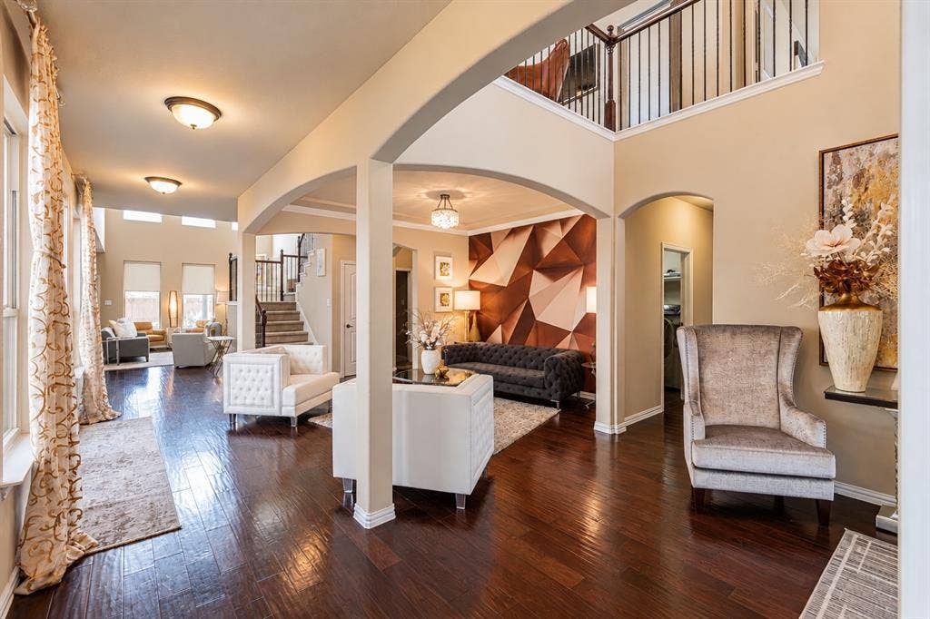 1704 Keswick Drive, McKinney, TX 75071 Two-story interior with dark wood-finish flooring, arched doorways, a coffered ceiling, and a second-story landing with black metal railing