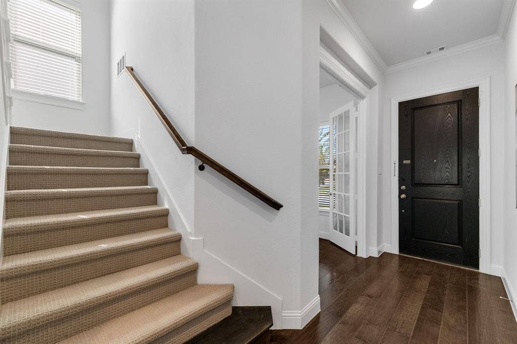 Staircase with carpeted treads and a wood handrail