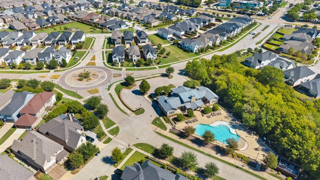 Community featuring a central roundabout, extensive green spaces, and a shared swimming pool with surrounding patio