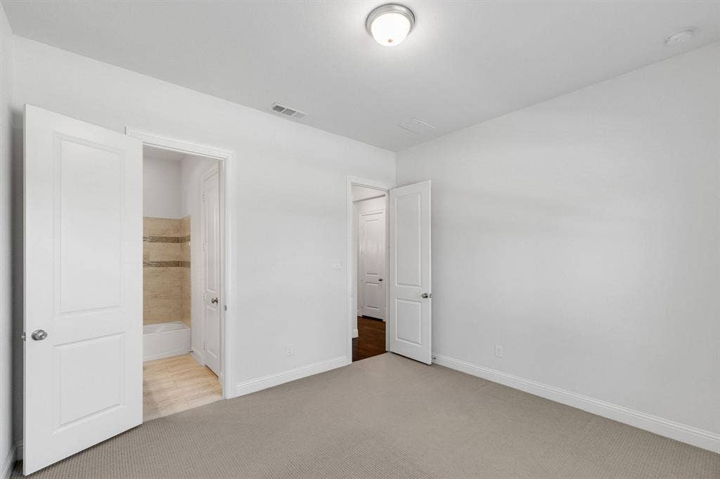First floor bedroom/ Downstairs bedroom- Plush carpeting, neutral wall tones, interior panel doors, and overhead flush mount lighting