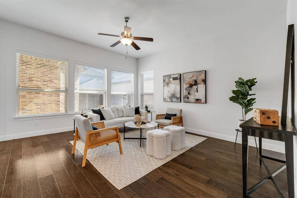 Wood-finish flooring, multiple windows with blinds, and a ceiling fan with integrated lighting