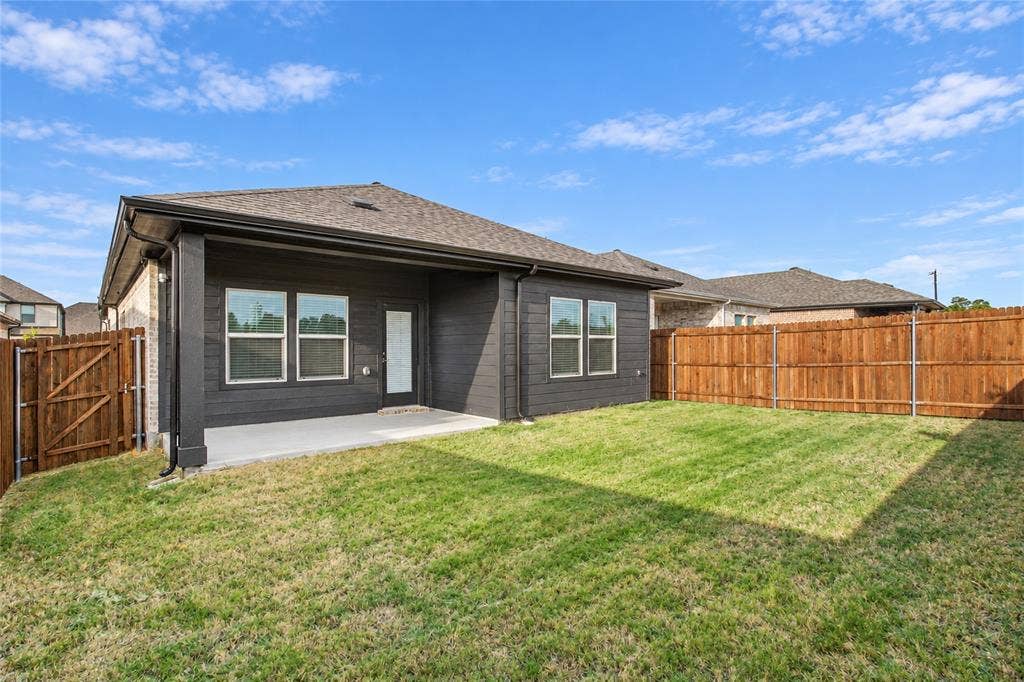 113 Greenbriar Drive, Princeton, TX 75071 Expansive backyard with a covered concrete patio, wood privacy fencing, and a manicured lawn