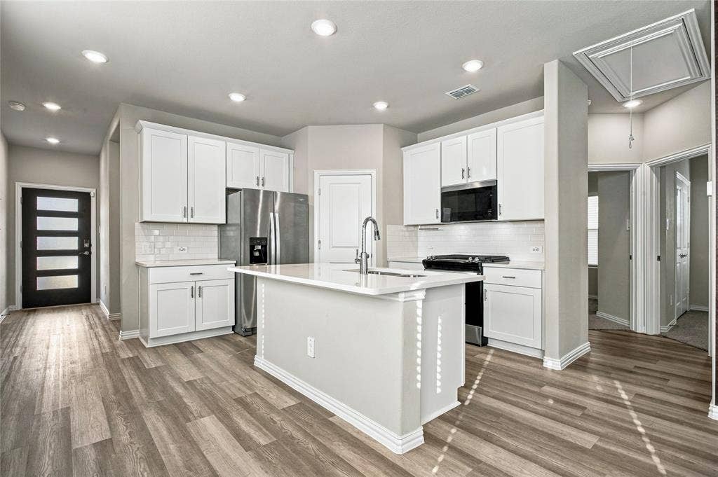 113 Greenbriar Drive, Princeton, TX 75071 Kitchen featuring an island with a sink, stainless steel appliances, white cabinetry, recessed lighting, and wood-finish flooring