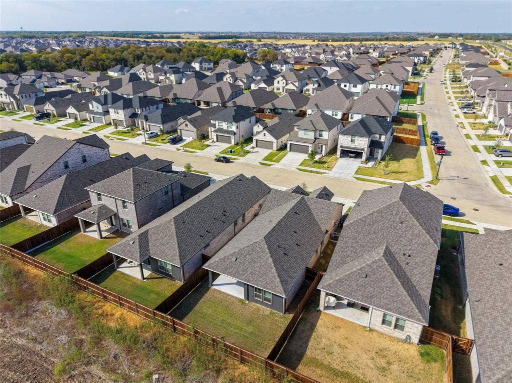 113 Greenbriar Drive, Princeton, TX 75071 Aerial perspective of a residential neighborhood featuring multiple single-family homes with gray shingle roofs, private fenced yards, and concrete driveways