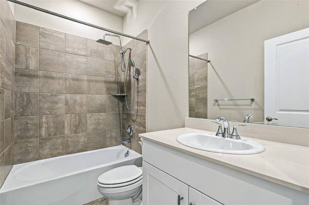 113 Greenbriar Drive, Princeton, TX 75071 Modern bathroom featuring a ceramic vessel sink with chrome faucet and widespread handles, white vanity cabinetry with ample storage, frameless glass shower enclosure, subway tile surround in neutral tones, and an integrated bathtub-shower combination with chrome fixtures