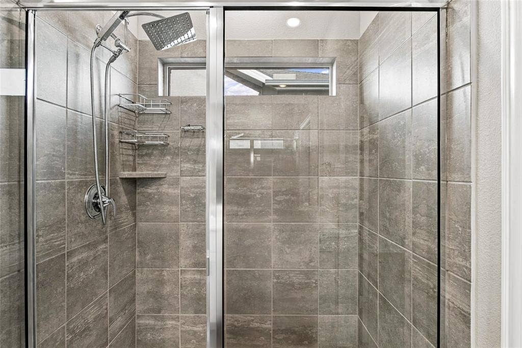 113 Greenbriar Drive, Princeton, TX 75071 Enclosed shower with full-height tile surround, built-in tile shelf, and multiple shower heads