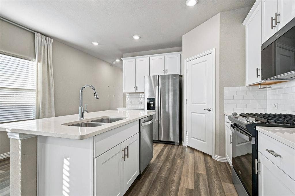 113 Greenbriar Drive, Princeton, TX 75071 Kitchen with white cabinetry, stainless steel appliances, wood-finish flooring, and recessed lighting