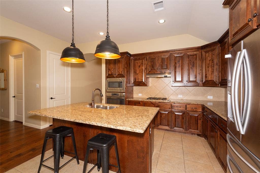 Kitchen featuring rich wood-finish cabinetry, light-toned countertops, and stainless steel appliances