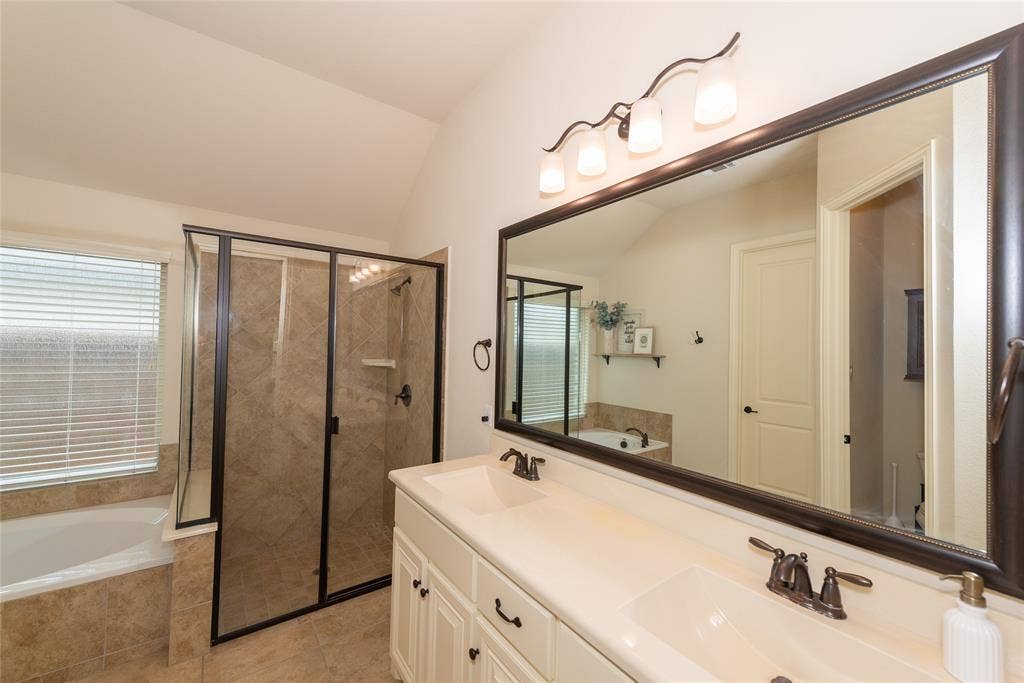 Dual vanity with undermount sinks, bronze fixtures, and a large framed mirror