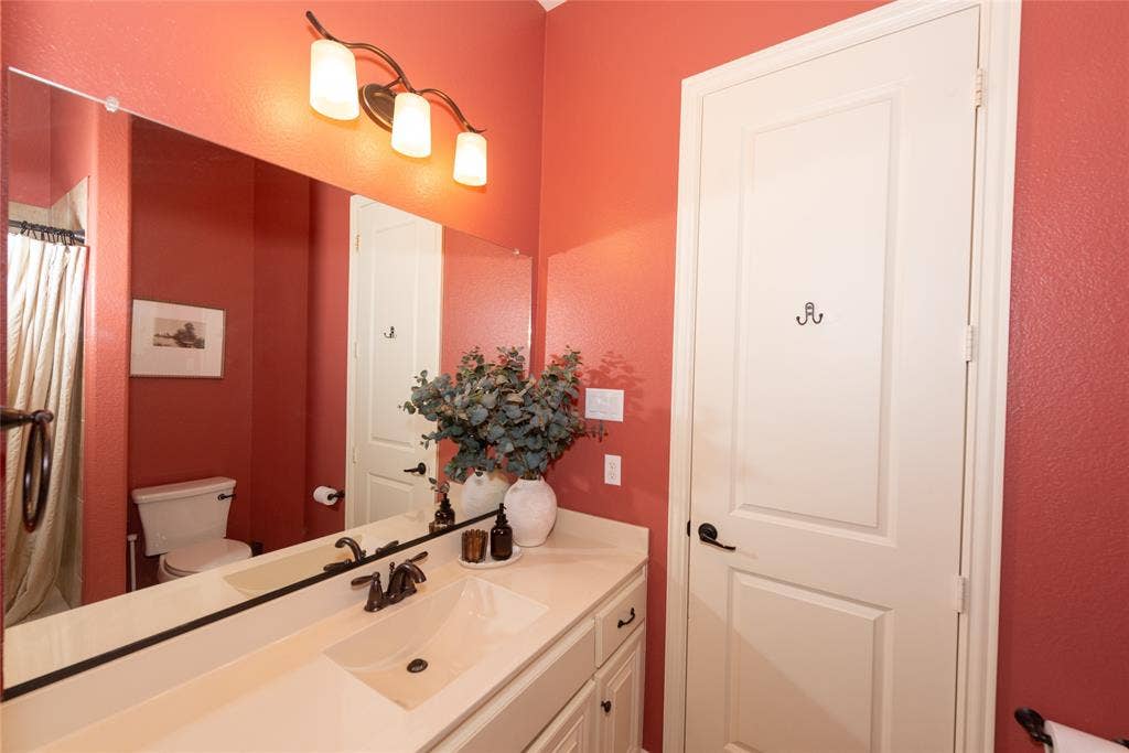 Double vanity with integrated sinks, bronze-finish fixtures, and full-width mirror