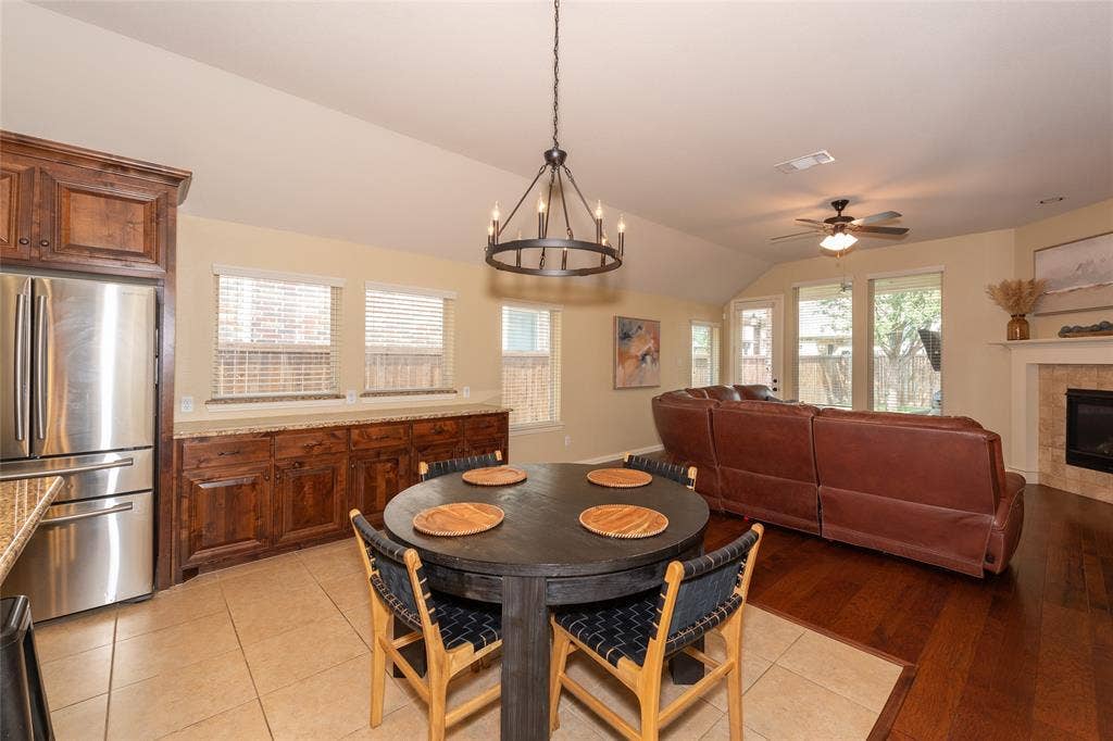 Vaulted ceiling, wood-finish flooring, custom wood cabinetry, stainless steel refrigerator, and a built-in fireplace