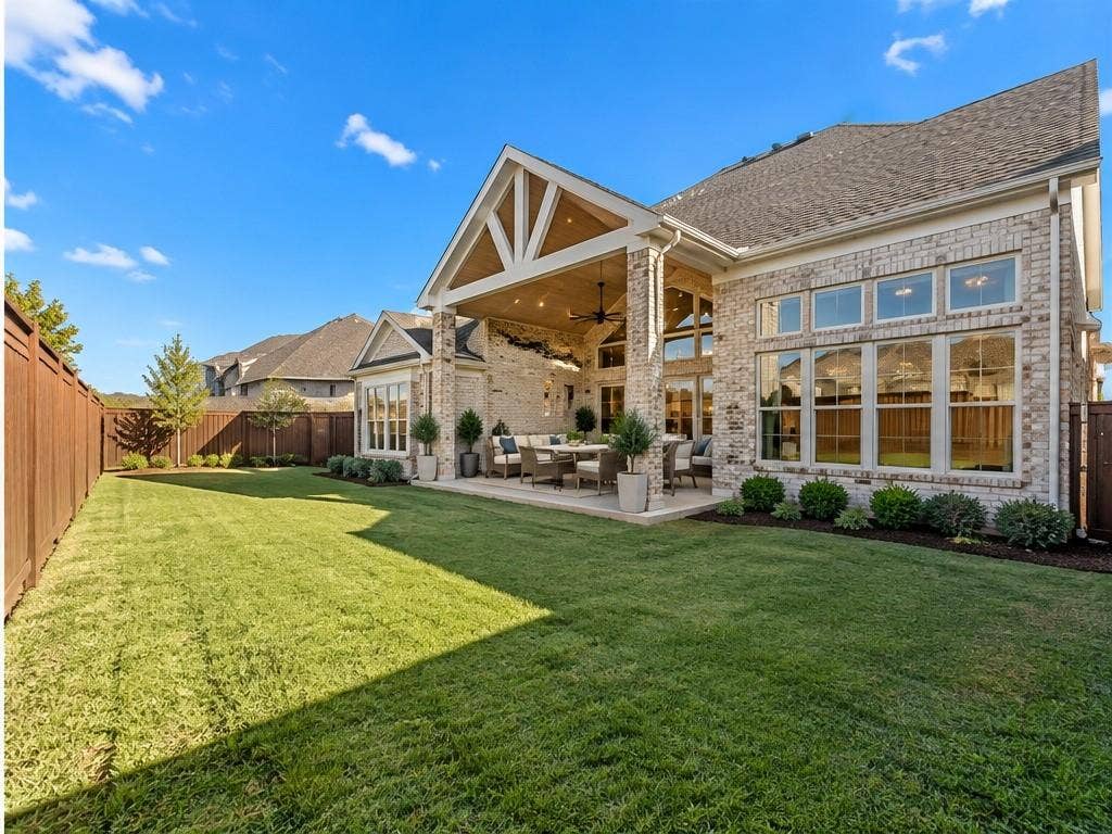 1320 Cartona Road, Fate, TX 75087 Expansive backyard with a covered patio, brick exterior, multiple large windows, and a wood privacy fence