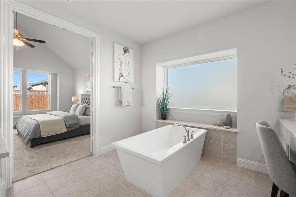 1320 Cartona Road, Fate, TX 75087 Freestanding bathtub with deck-mounted fixtures, large frosted window, and tile flooring