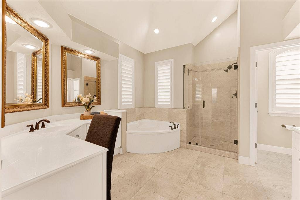 6429 GLENHOLLOW Drive, Plano, TX 75093 High vaulted ceilings and crisp neutral tile amplify soft light throughout the ensuite bath. Picture preparing for the day ahead in a bright, spa-inspired sanctuary.